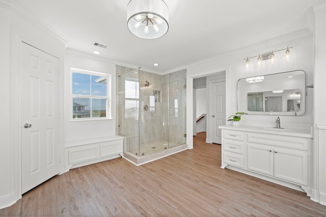 bathroom featuring vanity, wood finished floors, visible vents, ornamental molding, and a shower stall