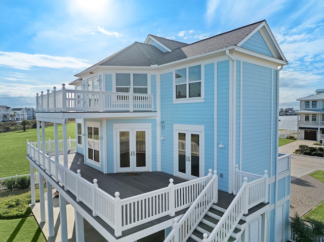 rear view of house featuring french doors, a lawn, roof with shingles, and a deck