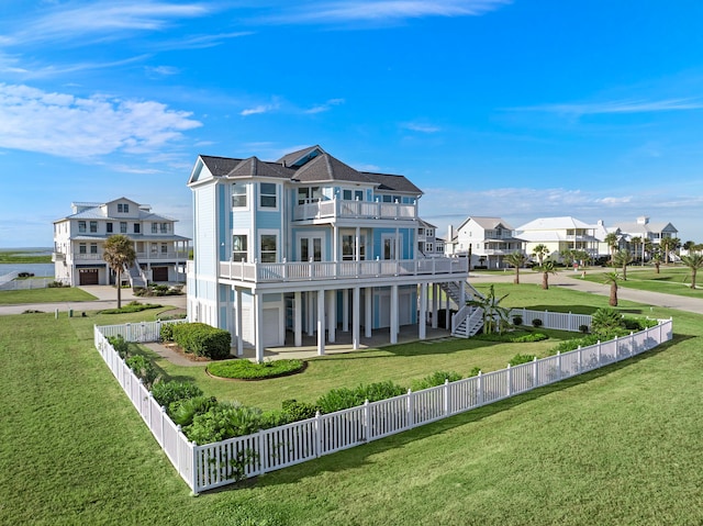 rear view of house with a fenced backyard, a residential view, a lawn, and a balcony