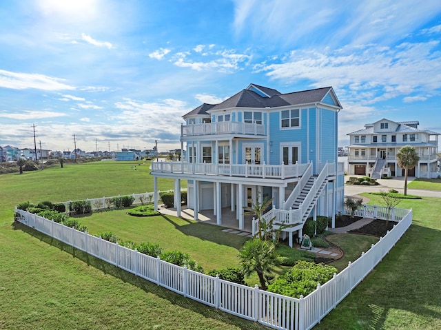 rear view of house featuring stairway, a lawn, a fenced backyard, a balcony, and a patio area