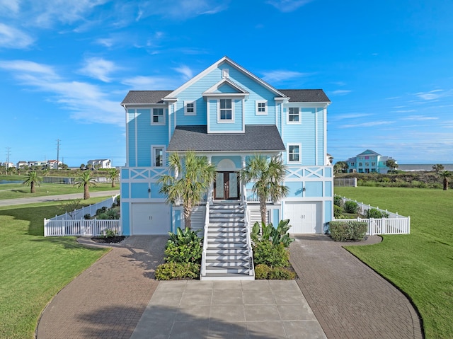 raised beach house featuring stairway, a porch, a front lawn, a garage, and decorative driveway