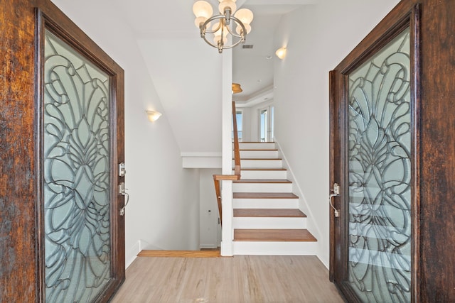 entryway featuring wood finished floors, visible vents, baseboards, stairs, and a notable chandelier