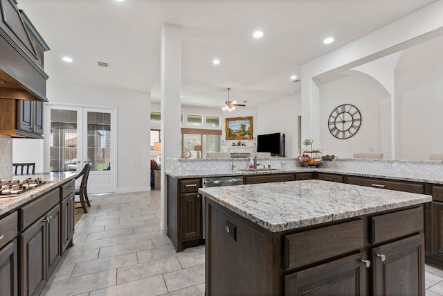 kitchen with dark brown cabinetry, ceiling fan, a center island, kitchen peninsula, and stainless steel gas stovetop