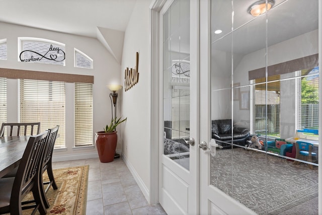 tiled dining space with french doors, vaulted ceiling, and a healthy amount of sunlight