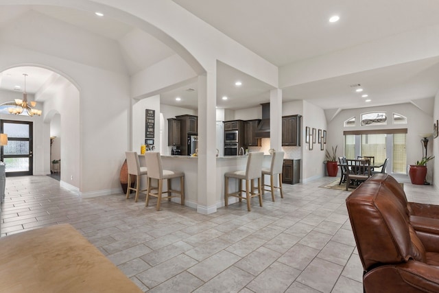 kitchen featuring kitchen peninsula, dark brown cabinetry, plenty of natural light, and a chandelier