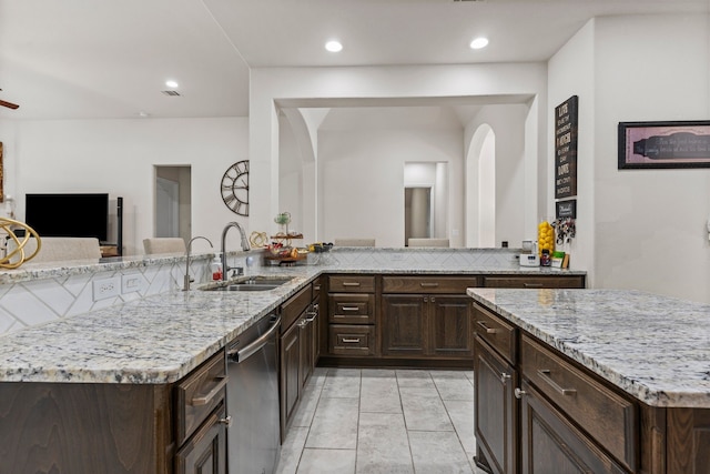 kitchen with stainless steel dishwasher, light stone countertops, kitchen peninsula, and sink