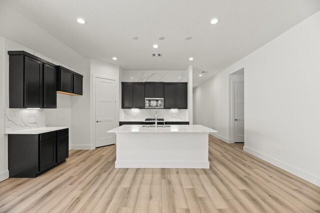 kitchen featuring stainless steel microwave, dark cabinets, and a sink