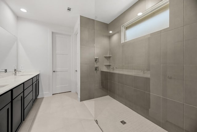 full bathroom featuring visible vents, a walk in shower, double vanity, tile patterned floors, and a sink