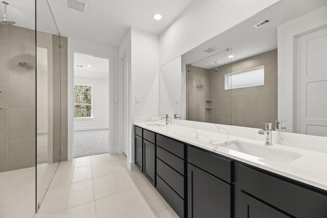 full bath featuring visible vents, double vanity, a sink, tile patterned flooring, and walk in shower