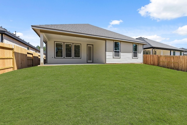 back of house with a patio, a lawn, roof with shingles, and a fenced backyard