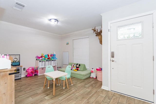 recreation room featuring light wood-type flooring and ornamental molding