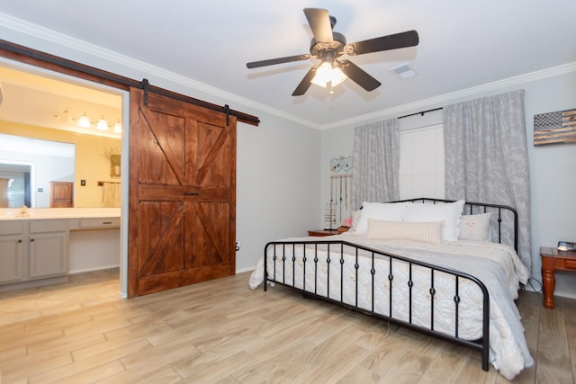 bedroom featuring ceiling fan, a barn door, ornamental molding, and ensuite bath