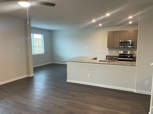 kitchen featuring ceiling fan, light stone countertops, dark wood-type flooring, and appliances with stainless steel finishes