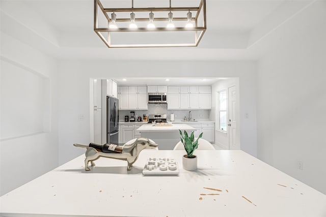 kitchen with a raised ceiling, white cabinetry, sink, and appliances with stainless steel finishes