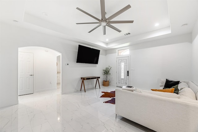 living room featuring a tray ceiling and ceiling fan