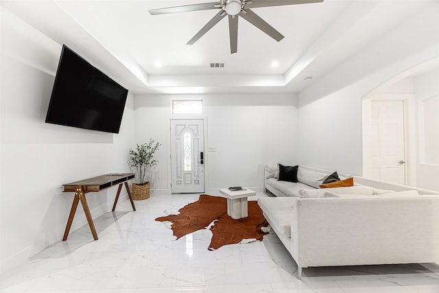 living room featuring a raised ceiling and ceiling fan