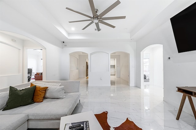 living room with ceiling fan and a tray ceiling