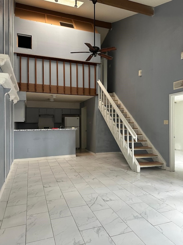 stairs with beamed ceiling, high vaulted ceiling, and ceiling fan