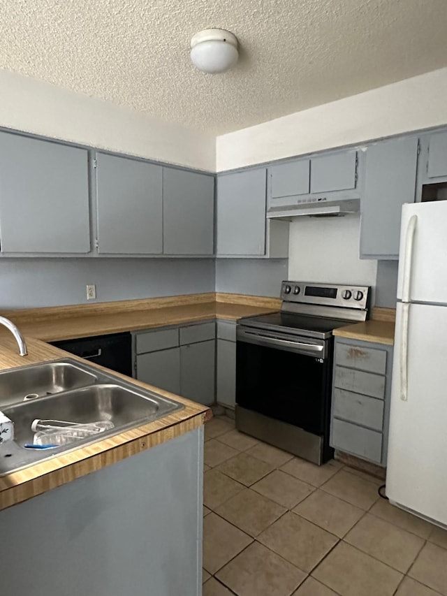 kitchen featuring gray cabinetry, a textured ceiling, light tile patterned floors, white fridge, and stainless steel electric range oven