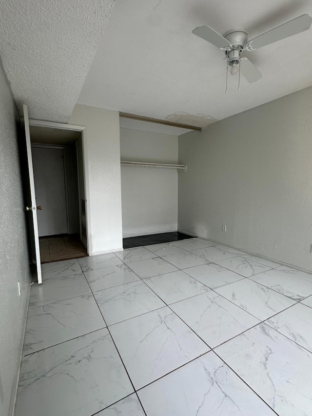 unfurnished bedroom with ceiling fan, a closet, and a textured ceiling