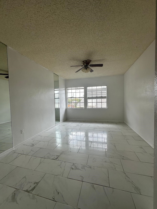 empty room with ceiling fan and a textured ceiling