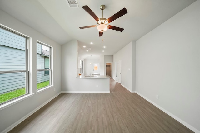 unfurnished living room with wood-type flooring, ceiling fan, and sink