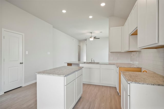 kitchen featuring sink, kitchen peninsula, light hardwood / wood-style flooring, a kitchen island, and white cabinetry