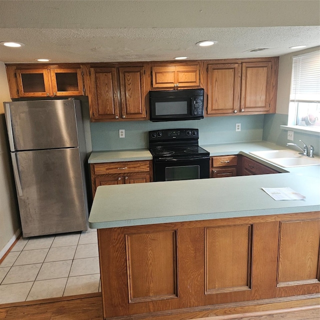 kitchen with black appliances, light tile patterned flooring, sink, and a textured ceiling