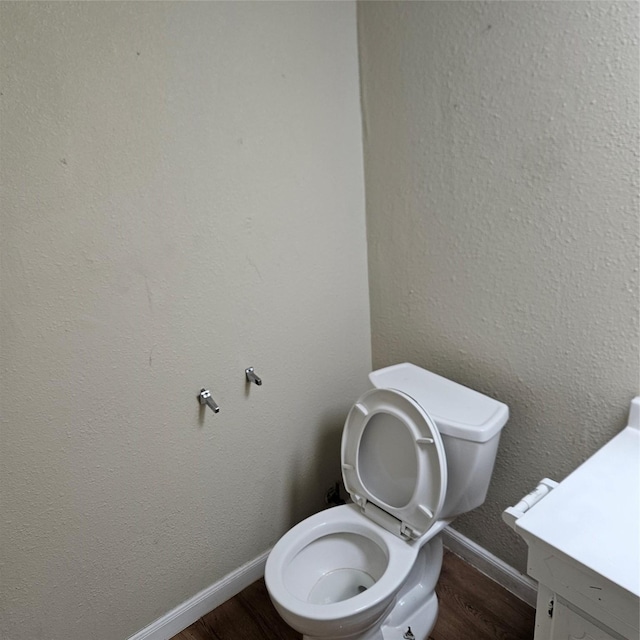 bathroom with toilet, vanity, and hardwood / wood-style floors