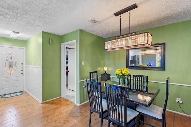 dining area with wood-type flooring and a textured ceiling