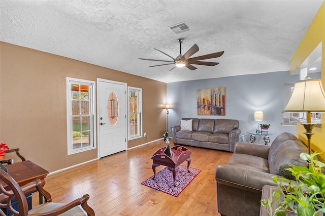 living room with hardwood / wood-style floors, ceiling fan, and a textured ceiling