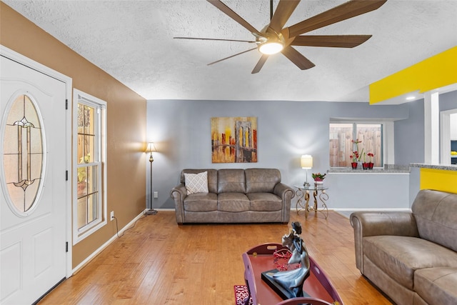 living room with ceiling fan, wood-type flooring, and a textured ceiling