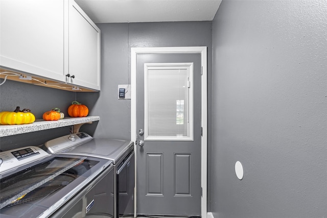 clothes washing area featuring cabinets and washer and clothes dryer