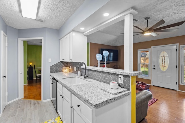 kitchen with white cabinets, light hardwood / wood-style floors, sink, and tasteful backsplash