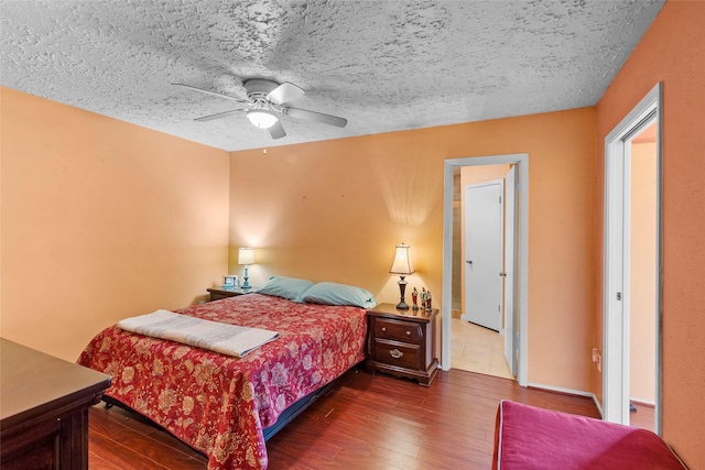 bedroom with ceiling fan, dark wood-type flooring, and a textured ceiling