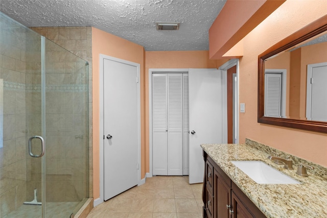 bathroom with tile patterned floors, a textured ceiling, vanity, and an enclosed shower