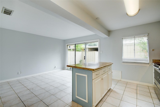 kitchen featuring light tile patterned floors, gas range, a kitchen island, and a healthy amount of sunlight