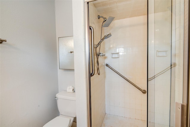 bathroom featuring toilet and a shower with shower door