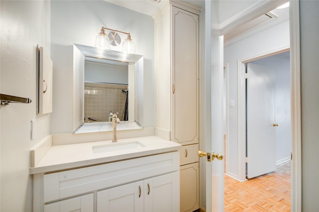 bathroom with a tile shower, vanity, parquet floors, and ornamental molding