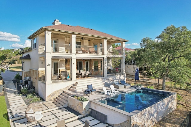 back of property with ceiling fan, a balcony, and a patio