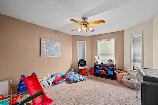 rec room with a textured ceiling, carpet floors, and ceiling fan