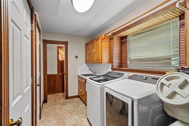 laundry room with cabinets, sink, wooden walls, and washing machine and clothes dryer