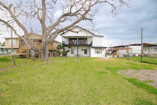 back of house featuring a lawn and a balcony