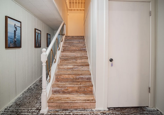 stairway featuring wooden walls