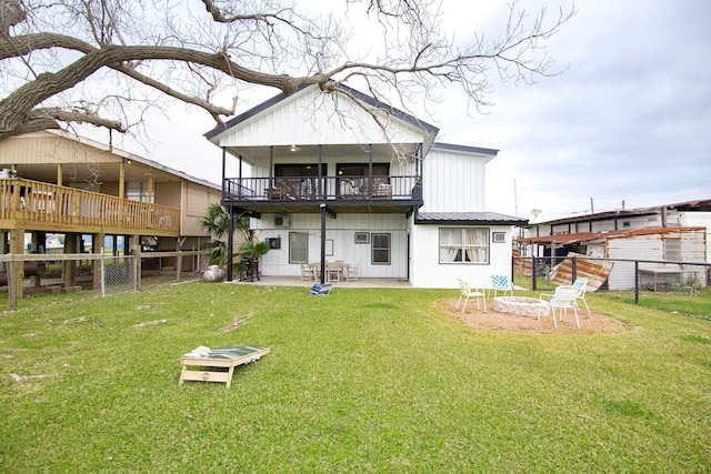 back of house with a yard, a balcony, a patio, and a fire pit