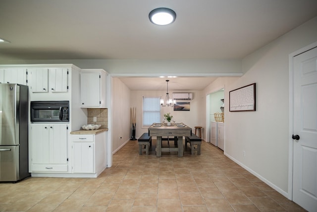 kitchen with an inviting chandelier, stainless steel fridge, decorative light fixtures, decorative backsplash, and white cabinets