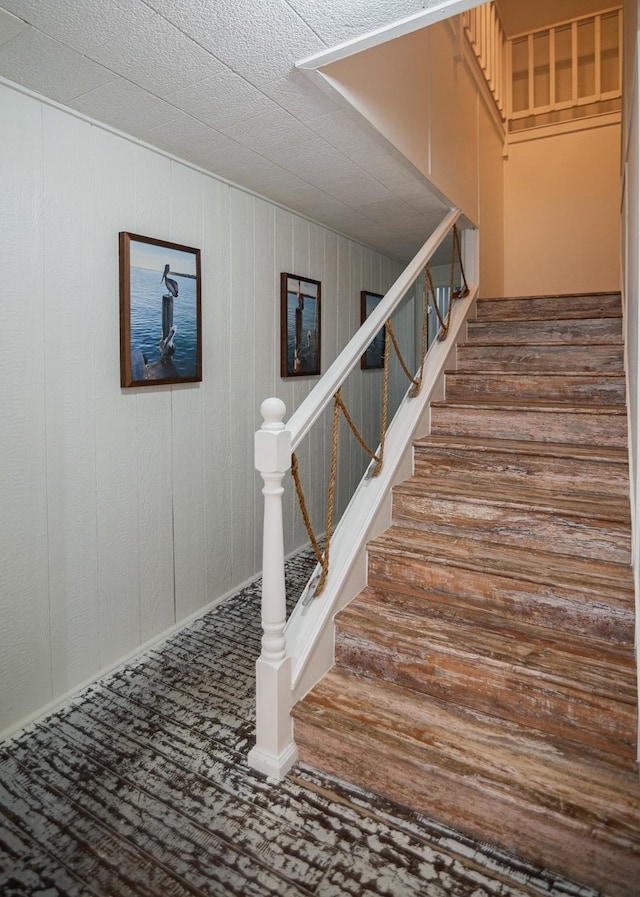 stairs with carpet and wood walls