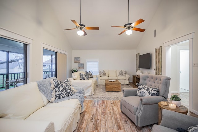 living room with hardwood / wood-style flooring, ceiling fan, and high vaulted ceiling