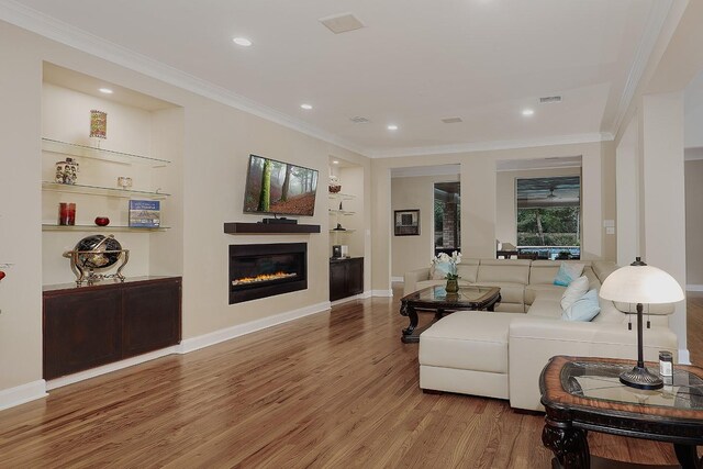 living room featuring hardwood / wood-style flooring, built in features, and ornamental molding