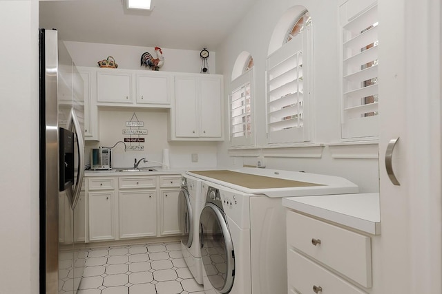 clothes washing area featuring washer and clothes dryer, cabinets, and sink